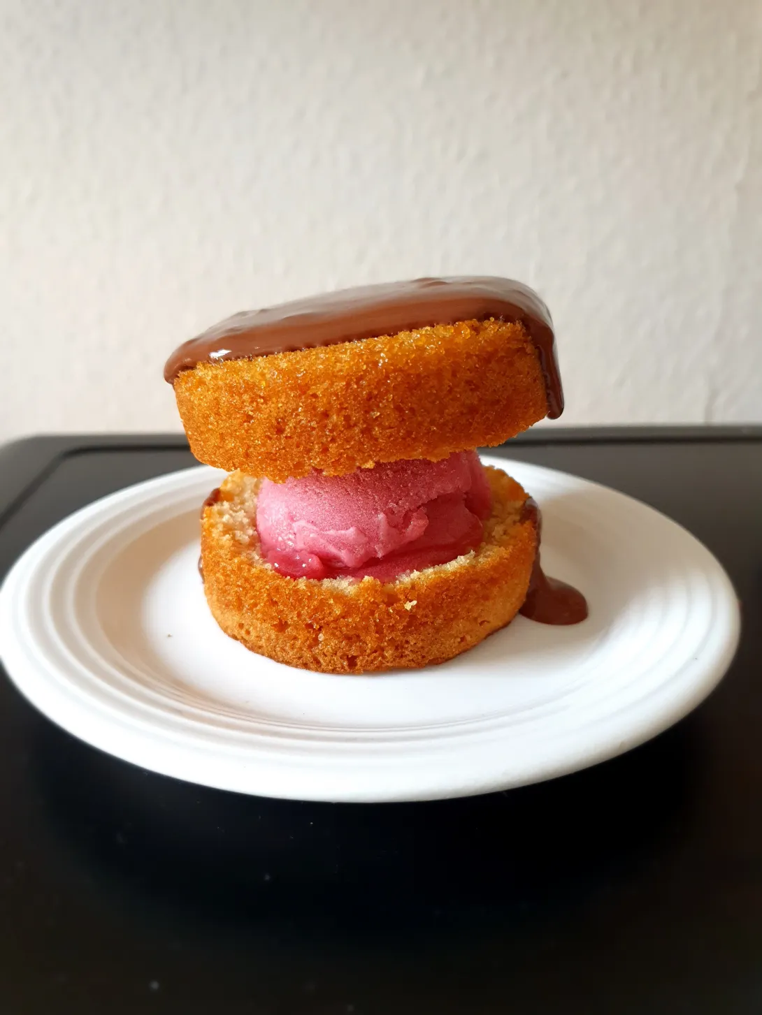 Het ijstaartje met chocoladesaus geserveerd op een wit schoteltje.